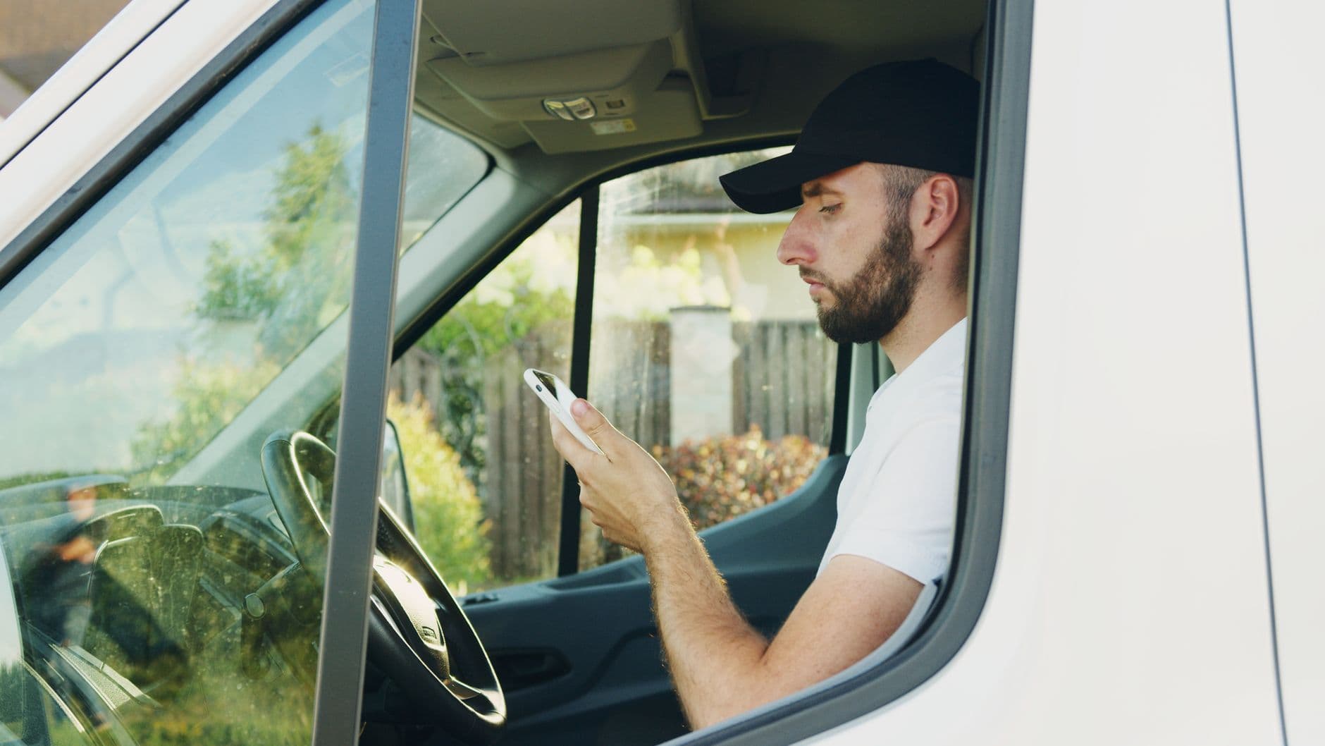 Conductor consultando su celular dentro del vehículo estacionado