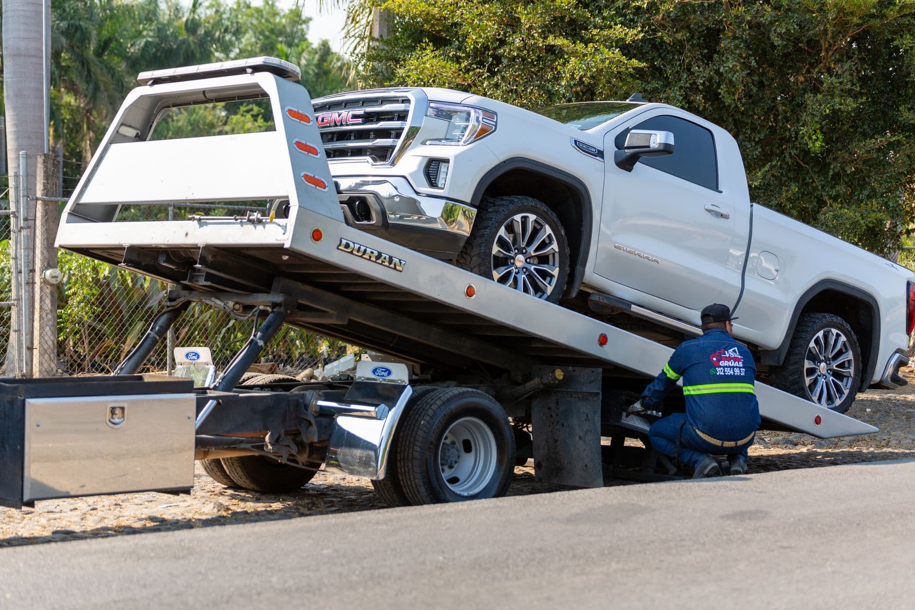 Operario de una grúa cargando una camioneta sobre la plataforma