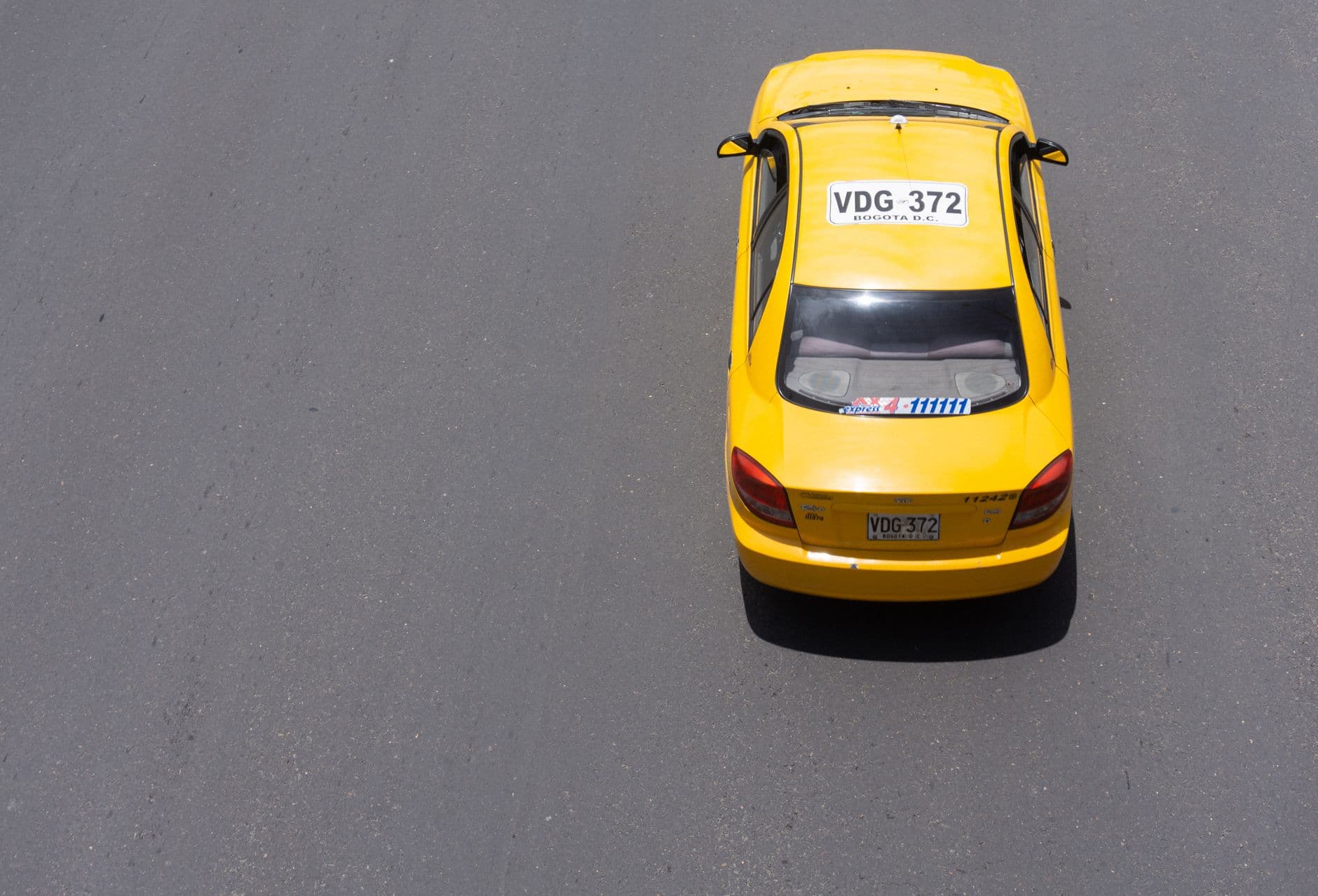 Vista aérea de un taxi amarillo circulando solo por una vía de Bogotá