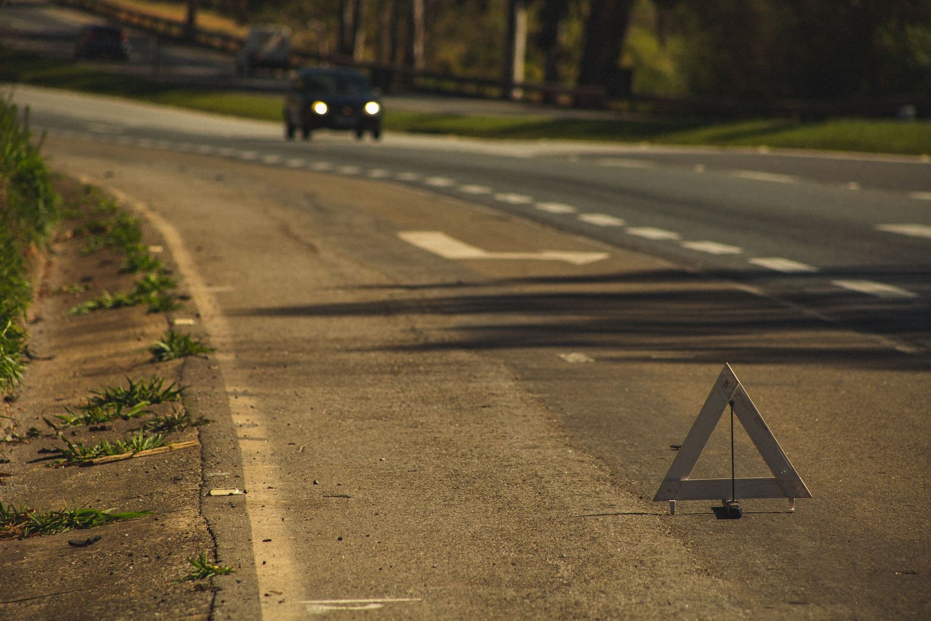 Triángulo reflectivo puesto sobre la berma de una carretera mientras se acerca un carro con las luces encendidas
